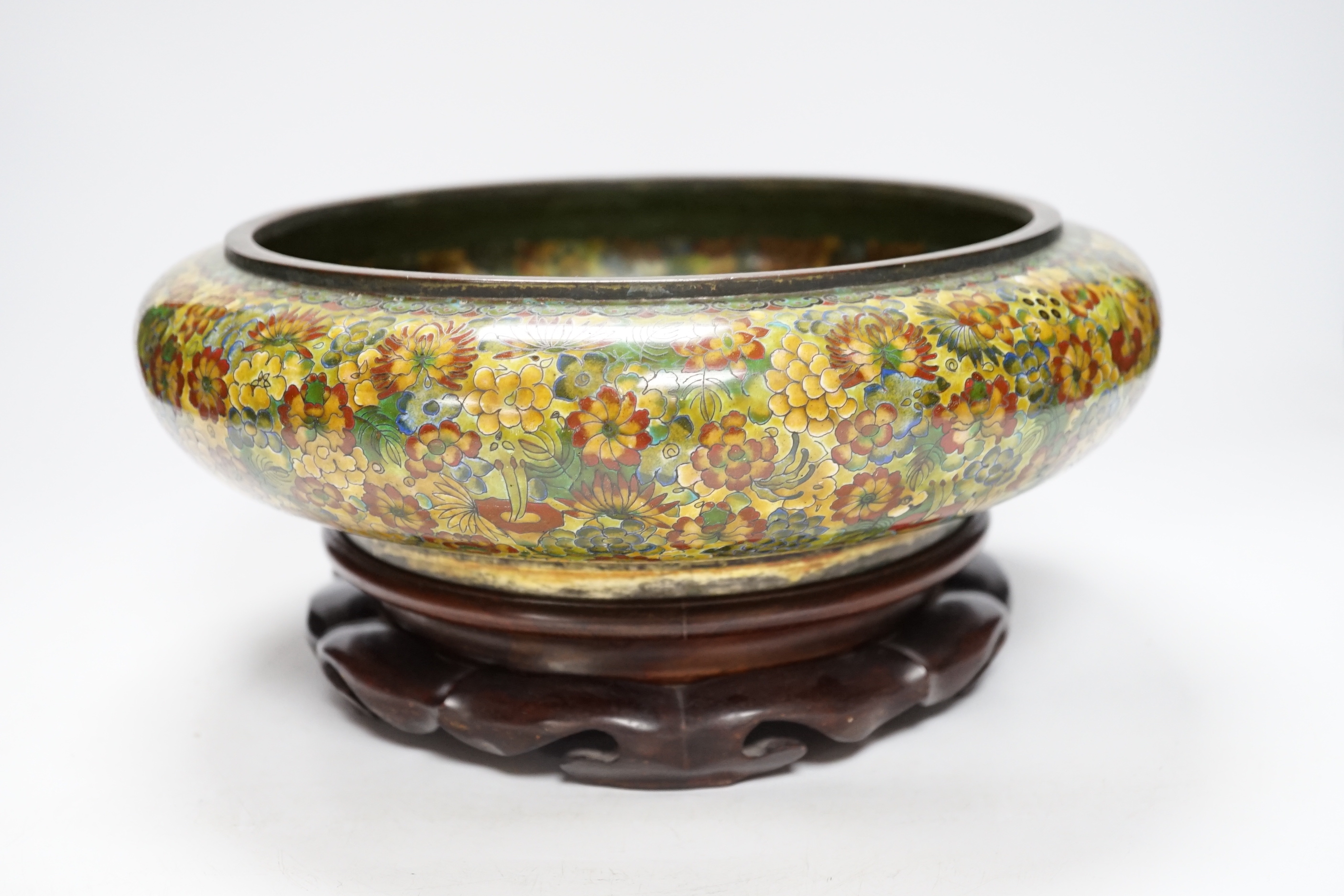 A Chinese circular cloisonné enamel bowl decorated with multi-coloured flowerheads on wooden stand, 30cm diameter
